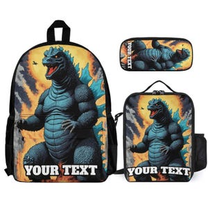 May include: A backpack, a lunch bag, and a pencil case set featuring a blue monster graphic against a fiery orange and yellow background. Each item displays the text YOUR TEXT in bold white letters at the bottom, with the monster standing tall.