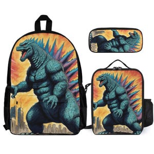 May include: A set of three items featuring a Godzilla design: a backpack, a pencil case, and a lunch bag. The items have a teal Godzilla illustration against a fiery orange and yellow background, with a cityscape at the bottom.