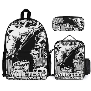 May include: A black and white backpack, lunch bag, and pencil case set featuring a graphic of a large monster in a city with Japanese text and the words YOUR TEXT printed at the bottom of each item. The design includes buildings and explosions.