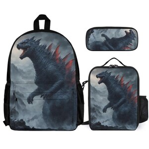 May include: A black backpack, pencil case, and lunch bag set. Each item features a detailed illustration of a dark blue monster with red dorsal fins against a misty, mountainous background. The backpack has side pockets.