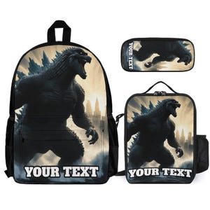 May include: A black backpack, a rectangular pencil case, and a lunch bag, each featuring a graphic of a dark, scaly monster standing in a city at sunset. The backpack and lunch bag display the text YOUR TEXT at the bottom, while the pencil case has it on the side.