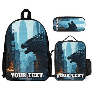 May include: A backpack, a lunch bag, and a pencil case set featuring a dark, scaly monster in a city street with skyscrapers. Each item displays the text YOUR TEXT in white block letters against the blue-toned urban scene with orange fire.