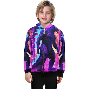 Op de afbeelding: Een paarse, roze en blauwe hoodie met rits en een grafische print van een monster in een stad.