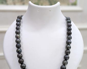 May include: A dark gray pearl necklace displayed on a white bust. The pearls are round and have a lustrous sheen. The necklace is a classic jewelry piece, suitable for formal occasions.