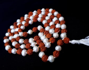 May include: A white and brown beaded necklace with a white tassel. The necklace is made of two strands of beads, one white and one brown.