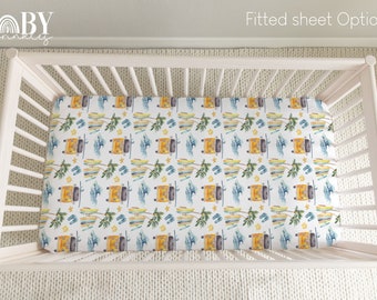 May include: A white fitted crib sheet with a yellow, blue, and green watercolor pattern of surfboards, palm trees, and flip flops. The sheet is in a crib with white wooden slats. The text "Fitted sheet Option 1" is visible in the top right corner of the image.