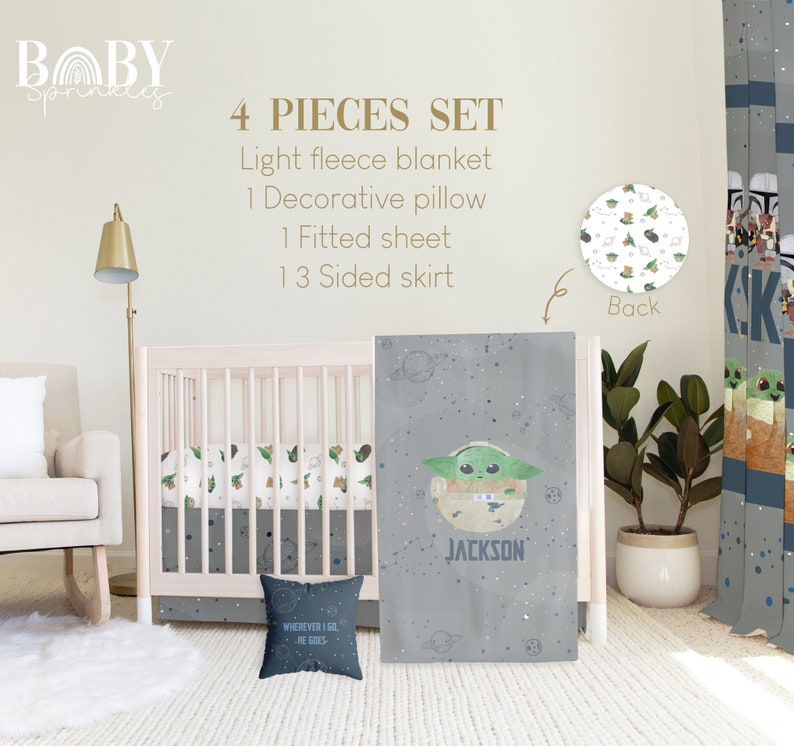 Op de afbeelding: Een vierdelige babybeddenset met een grijs en wit ruimtethema met een groen alienfiguur. De set bevat een licht fleece deken, een decoratief kussen, een hoeslaken en een 13-zijdige rok. Het kussen heeft de tekst "WHEREVER I GO HE GOES" erop gedrukt. De rok heeft de naam "JACKSON" erop gedrukt.