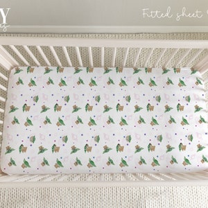 May include: A white crib with a fitted sheet featuring a repeating pattern of green and brown baby Yoda characters with pink and blue dots. The sheet is labeled "Fitted sheet Option | Baby Sprinkles".