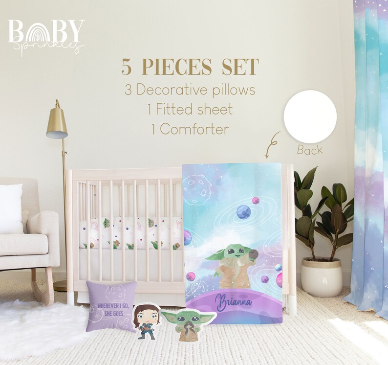 May include: A 5-piece baby bedding set featuring a watercolor design of a green alien character with planets and stars. The set includes a comforter, fitted sheet, and three decorative pillows. The comforter has the text "Brianna" on it. The pillows have the text "Wherever I go, she goes".