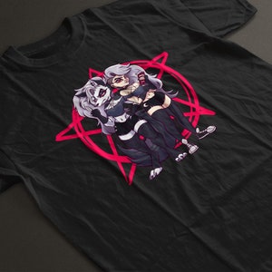 Può includere: Maglietta nera con un pentagramma rosa e un'immagine di cartone animato di due donne con orecchie e code di lupo.