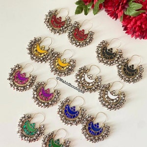 Puede incluir: Un conjunto de 10 pares de pendientes de aro de plata con detalles de vidrio de colores. Cada par presenta una forma de media luna con un diseño de vidrio de color diferente. Los pendientes están decorados con pequeñas cuentas de plata.