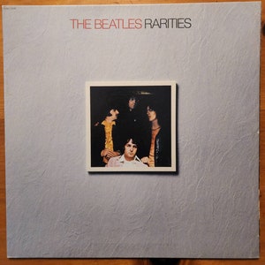 May include: A vintage vinyl record album cover featuring a black and white photo of the Beatles. The album title "THE BEATLES RARITIES" is printed in red letters on a gray background.