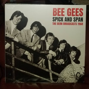 May include: A black and white photo of the Bee Gees band members on a record album cover. The album title is "Spick and Span" and the subtitle is "The Bern Broadcasts 1968".