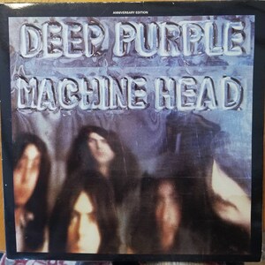 May include: A vintage vinyl record album cover featuring the band Deep Purple. The album title "Machine Head" is printed in large, bold letters on a silver background. The cover art features a blurry image of the band members.