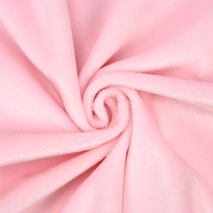 May include: A close-up of soft, pink fabric with a smooth, velvety texture. The fabric is folded and twisted, creating a swirling pattern.