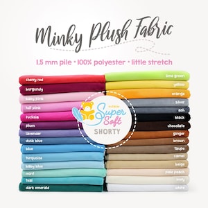 May include: A stack of 1.5 mm pile minky plush fabric swatches in various colors, including cherry red, burgundy, baby pink, hot pink, fuchsia, plum, lavender, dusk blue, blue, turquoise, baby blue, mint, teal, dark emerald, lime green, yellow, orange, silver, ash, black, chocolate, ginger, brown, taupe, camel, beige, pale peach, ivory, and white. The fabric is 100% polyester and has a little stretch. The text "Super Soft Shorty" is printed on a white circle with a pink border.
