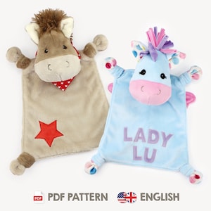 Könnte beinhalten: Zwei Plüsch-Sicherheitsdecken in Form eines Pferdes. Eine ist braun mit einem roten Stern und einem roten Bandana. Die andere ist blau mit rosa und violetten Akzenten und dem Namen "Lady Lu" in lila gestickt.