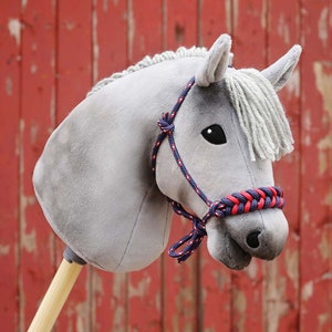 Pu&ograve; includere: Una testa di cavallo di peluche grigia con un morso di corda intrecciata rosso e blu. Il cavallo ha una criniera e una coda bianche.