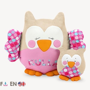 May include: Two plush owl toys. The larger owl is beige, pink, and orange, with the name "KULLA" embroidered on the front. The smaller owl has a similar design. Both owls have polka-dot wings in shades of pink, blue, and white.