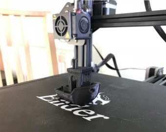 May include: A black 3D printed model of a small boat with a chimney on the roof. The boat is sitting on a black surface with the word "Ender" printed on it.