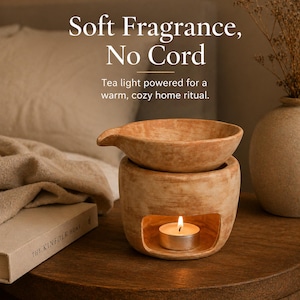 Könnte beinhalten: Ein beigefarbener Keramik-Duftdiffusor mit einer Teelichtkerze im Inneren. Der Diffusor hat einen runden Sockel und eine separate obere Schale. Der Text "Soft Fragrance, No Cord" ist im Bild zu sehen.