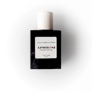 Può includere: Un flacone di profumo nero con un tappo bianco. L'etichetta riporta "authentic oud and vetiver APOTEOSI extrait extreme ScentGraphy Rome".