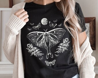May include: Black t-shirt with a white graphic of a luna moth, flowers, and a crescent moon.