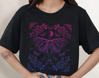 Może przedstawiać: Czarny T-shirt z nadrukiem graficznym przedstawiającym ćmę, kwiaty i półksiężyc. Grafika jest w odcieniach różowego i fioletowego.