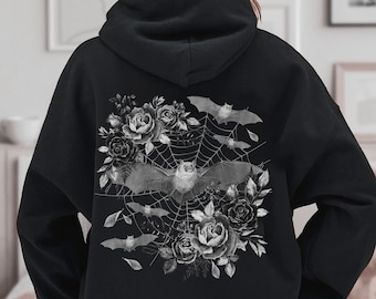 May include: Black hoodie featuring a grayscale floral and bat design. The graphic includes roses, spiderwebs, and bats. The design is centered on the back of the hoodie, creating a gothic aesthetic.