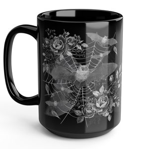 Pu&ograve; includere: Tazza in ceramica nera con un design bianco di pipistrelli, rose e una ragnatela.