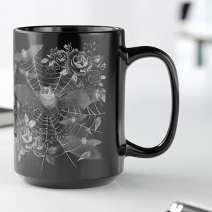Pu&ograve; includere: Tazza da caff&egrave; in ceramica nera con un design bianco di pipistrelli, rose e una ragnatela.