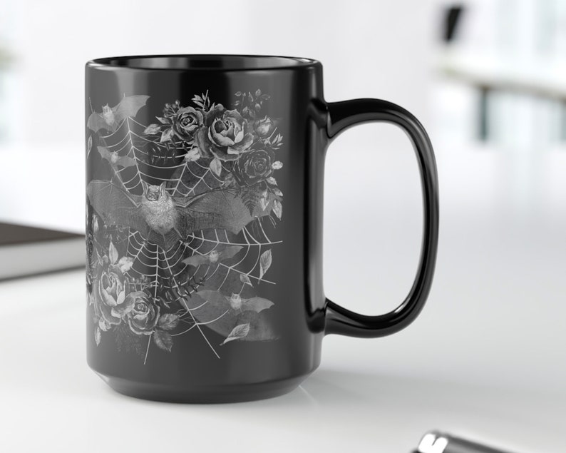 Pu&ograve; includere: Tazza da caff&egrave; in ceramica nera con un design bianco di pipistrelli, rose e una ragnatela.