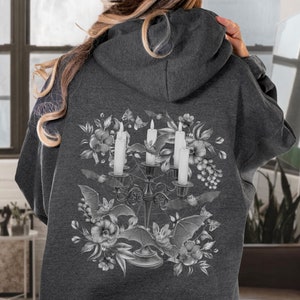 May include: A dark grey hoodie with a white graphic print of a candelabra with three candles, bats, and flowers. The graphic is centred on the back of the hoodie.