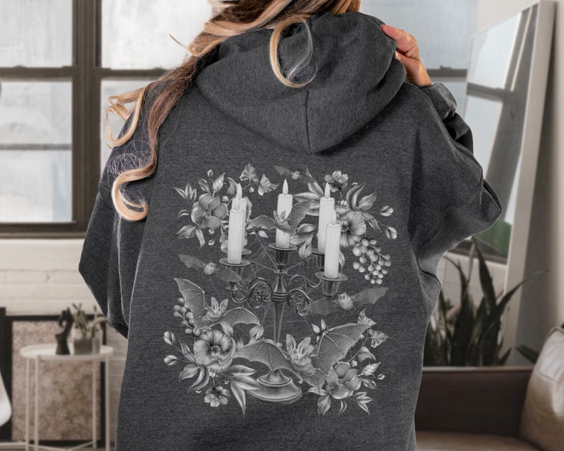 May include: A dark grey hoodie with a white graphic print of a candelabra with three candles, bats, and flowers. The graphic is centred on the back of the hoodie.