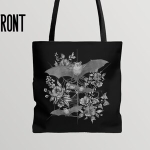 May include: Black tote bag with a white design of bats and flowers. The bats are flying in a web-like pattern with flowers surrounding them.