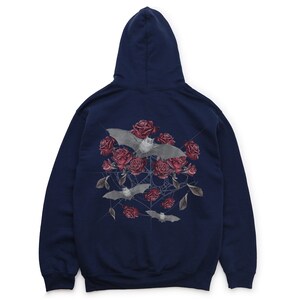 May include: Navy blue hoodie featuring a graphic of bats, red roses, and a spiderweb design. The hooded sweatshirt has a drawstring and a kangaroo pocket. The back of the hoodie displays the graphic.