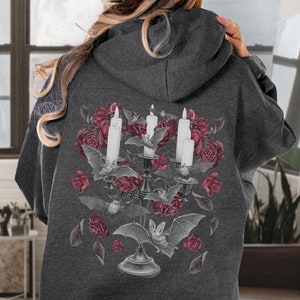 May include: A dark gray hoodie with a graphic print of a candelabra with three white candles, bats, and red roses.