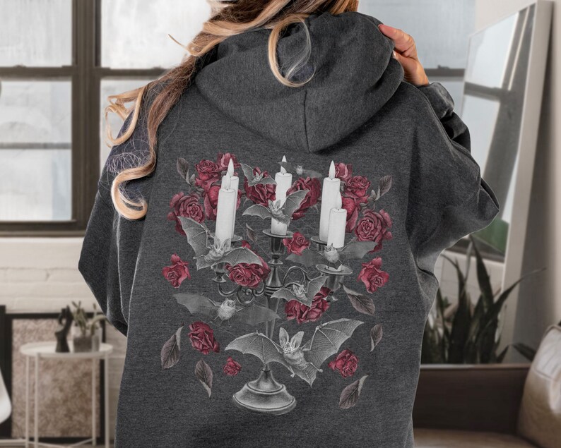 May include: A dark gray hoodie with a graphic print of a candelabra with three white candles, bats, and red roses.
