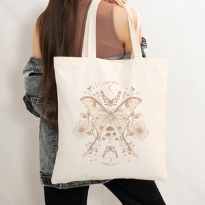 May include: A beige tote bag featuring a brown butterfly design and the text "Stay Wild Moon Child".
