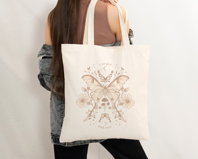 May include: A beige tote bag featuring a brown butterfly design and the text "Stay Wild Moon Child".