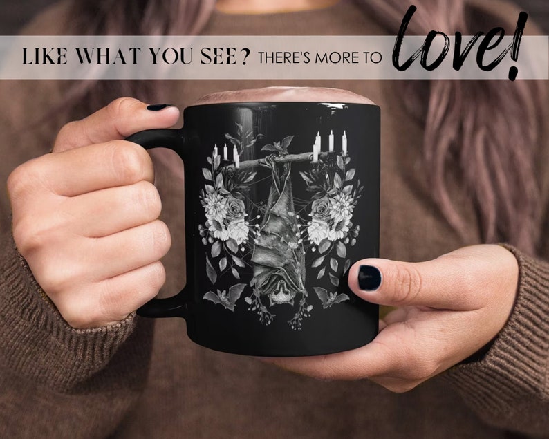 May include: Black ceramic mug featuring a white graphic of a bat hanging upside down from a branch with candles and flowers. The text "love!" is in the top right corner of the image.