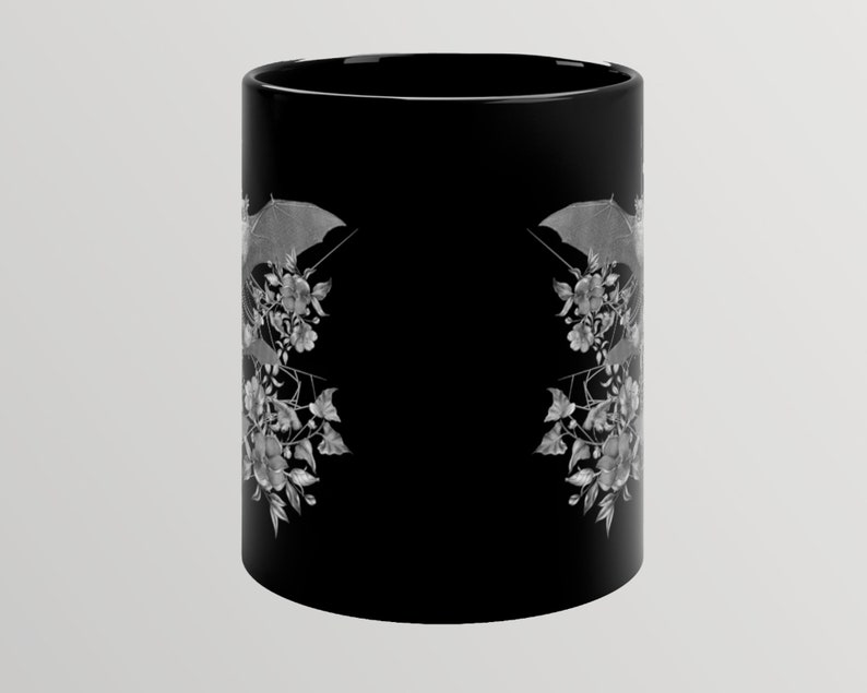 May include: Black ceramic mug with a white design of bats and flowers. The design is mirrored on both sides of the mug.