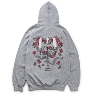 May include: A gray hooded sweatshirt with a graphic print of a candelabra with candles and roses. The candelabra is surrounded by bats and leaves.