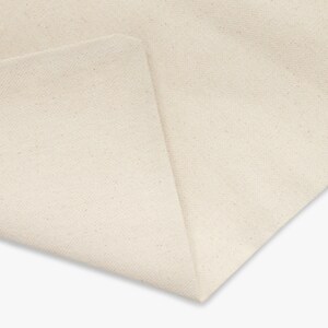 May include: Close-up of a plain, off-white fabric with a slightly textured surface.