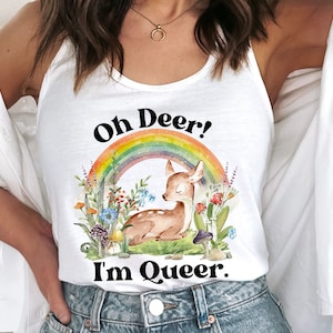 May include: White tank top with a rainbow and a deer illustration. The text "Oh Deer! I'm Queer." is printed on the shirt.