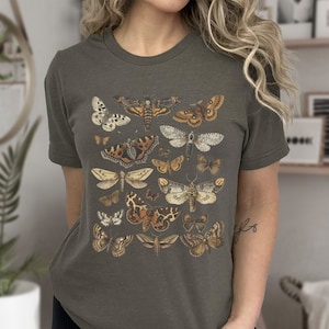 May include: A dark gray t-shirt with a vintage illustration of various butterflies and moths in shades of brown, white, and black.