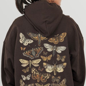 May include: A brown hooded sweatshirt featuring a print of assorted butterflies and moths in shades of brown, white, and black.