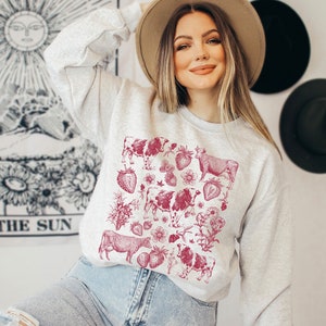 May include: A gray sweatshirt with a red vintage-style print of cows and strawberries. The print is centered on the front of the sweatshirt.