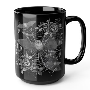 Pu&ograve; includere: Tazza da caff&egrave; in ceramica nera con un design bianco di pipistrelli che volano intorno a una ragnatela con rose.