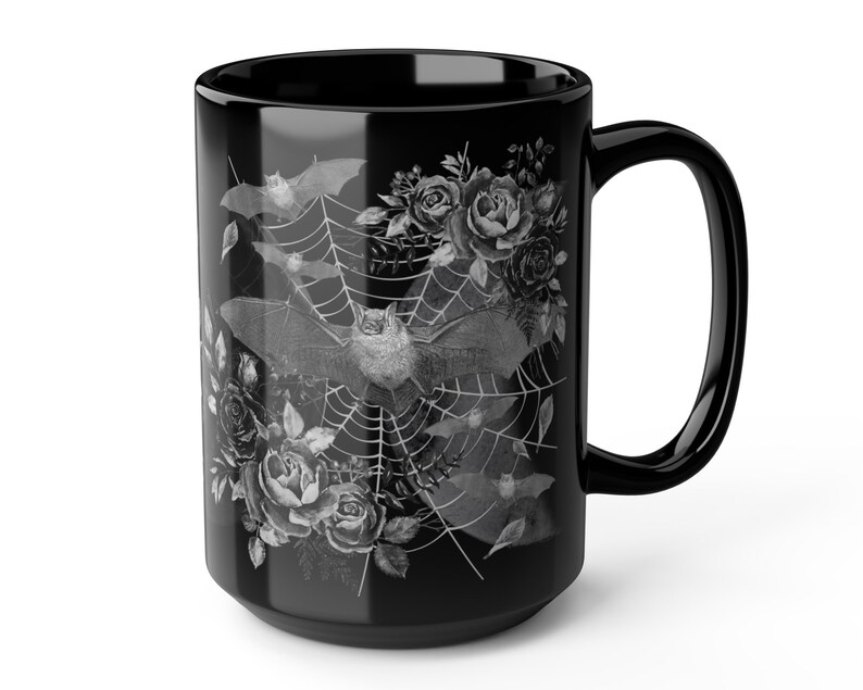 Pu&ograve; includere: Tazza da caff&egrave; in ceramica nera con un design bianco di pipistrelli che volano intorno a una ragnatela con rose.
